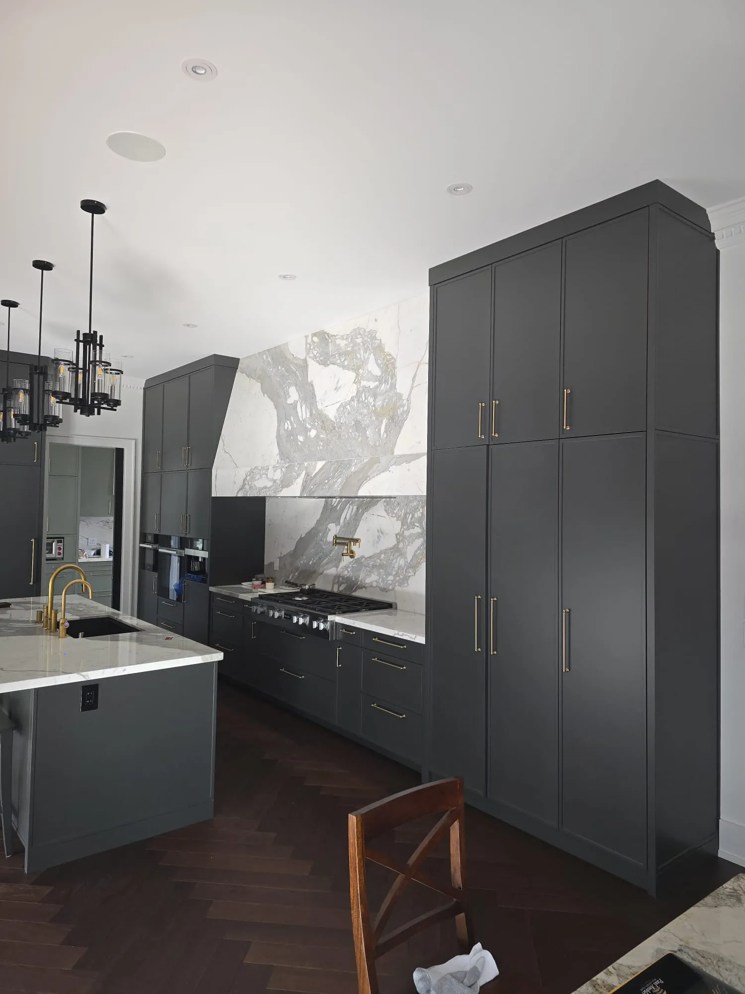 Charcoal custom kitchen with a marble island and brass faucet